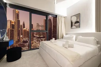 a bedroom with a large white bed and a large window at Restay Homes at Act Towers by Emaar - Pool access with Burj View included - Luxury Apartments in Downtown in Dubai