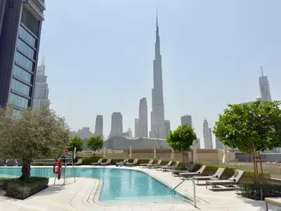 a pool with lounge chairs and a city skyline at Vida Dubai Mall Connected 1BR in Dubai
