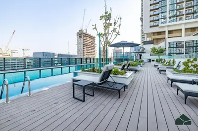 a rooftop deck with chairs and a pool on a building at Stylish 1BR with City and Partial Burj View by BMS in Dubai