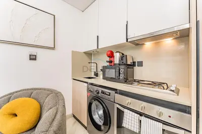 a kitchen with a washing machine next to a stove at Studio with Community Views, Easy Access to Bus Stop, Parks, and Circle Mall, Empire Residence, JVC by Deluxe Holiday Homes in Dubai