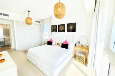 a white bedroom with a white bed and pink pillows at Resort lifestyle, Fantastic Views, Bright & Brand new in Dubai