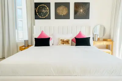 a bedroom with a large white bed with pink pillows at Resort lifestyle, Fantastic Views, Bright & Brand new in Dubai