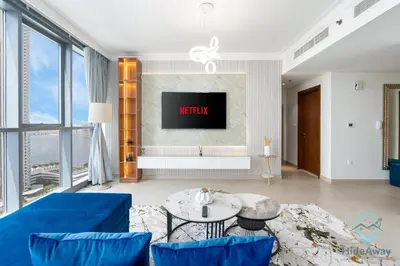 a living room with a blue couch and a tv at Waterfront Breathtaking 2BR Pool Burj Views Sleeps 7 in Dubai