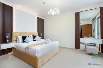 a bedroom with a large bed and a desk at Waterfront Breathtaking 2BR Pool Burj Views Sleeps 7 in Dubai