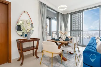 a living room with a table and a blue couch at Waterfront Breathtaking 2BR Pool Burj Views Sleeps 7 in Dubai