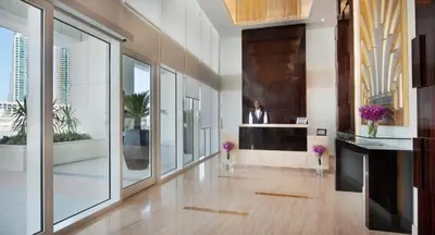 a large room with a lobby with windows and flowers at Damac Maison Canal Views, Luxury Waterfront Apartment, 2 BR, Dedicated Office, Sleeps 6 in Dubai