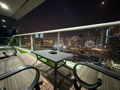 a table and chairs on a balcony with a city skyline at Damac Maison Canal Views, Luxury Waterfront Apartment, 2 BR, Dedicated Office, Sleeps 6 in Dubai