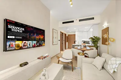 a living room with a couch and a tv at Bright & Cozy 1BR Apartment with Balcony in JVC in Dubai