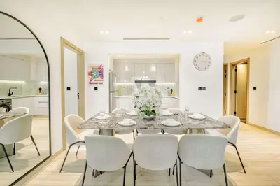 a dining room with a table and white chairs at PVH - Binghatti Heights - Urban Luxury 3BR in Dubai
