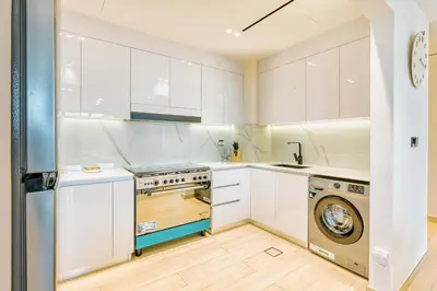 a kitchen with white cabinets and a washer and dryer at PVH - Binghatti Heights - Urban Luxury 3BR in Dubai