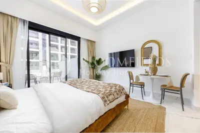 a bedroom with a bed and a table and chairs at Bloomfields Elegant Stu in Azizi Rivera in Dubai
