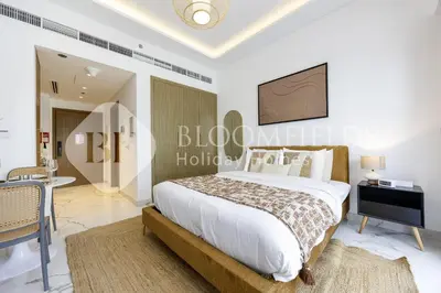 a bedroom with a bed and a desk and a television at Bloomfields Elegant Stu in Azizi Rivera in Dubai