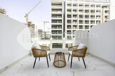 a balcony with chairs and a table and a building at Bloomfields Elegant Stu in Azizi Rivera in Dubai
