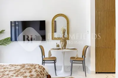 a room with a table with chairs and a mirror at Bloomfields Elegant Stu in Azizi Rivera in Dubai