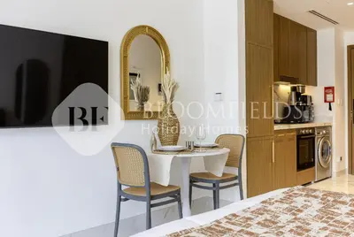 a dining room with a table and chairs and a mirror at Bloomfields Elegant Stu in Azizi Rivera in Dubai