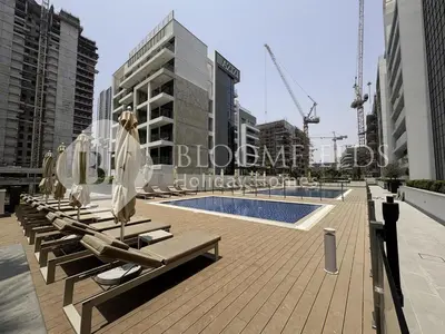 a row of lounge chairs with umbrellas next to a pool at Bloomfields Elegant Stu in Azizi Rivera in Dubai