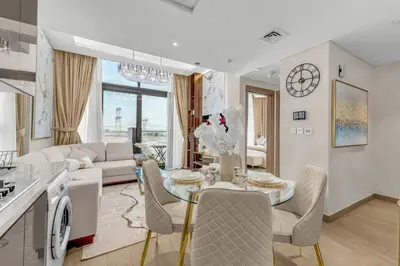 a kitchen and living room with a table and chairs at Stylish 1BR with Pool Gym and Parking in Riviera 12 in Dubai