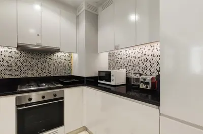 a white kitchen with white cabinets and appliances at Gogoto4 - 2BR High Floor Burj View Infinity Pool PS5 NYE Fireworks View in Dubai