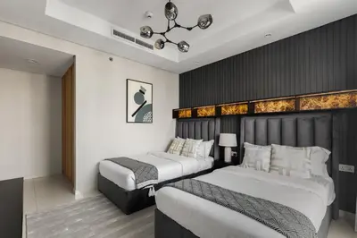a hotel room with two beds and a chandelier at Gogoto4 - 2BR High Floor Burj View Infinity Pool PS5 NYE Fireworks View in Dubai