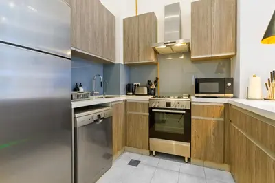 a kitchen with wooden cabinets and a stainless steel refrigerator at Modern House with Huge Private Garden in JVC in Dubai
