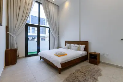 a bedroom with a bed and a large window at Modern House with Huge Private Garden in JVC in Dubai