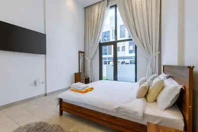 a bedroom with a bed with a large window at Modern House with Huge Private Garden in JVC in Dubai