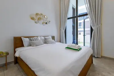 a bedroom with a large white bed with a window at Modern House with Huge Private Garden in JVC in Dubai