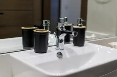 a bathroom sink with two cups and a faucet at Modern House with Huge Private Garden in JVC in Dubai
