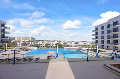 a view of a swimming pool with chairs and buildings at Luxury 1BR Apartment Dubai in Dubai