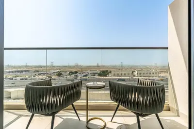 a balcony with two chairs and a table in front of a window at Chic Studio APT with Pool & Gym - Near Metro Station in Dubai