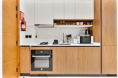 a kitchen with white cabinets and a black oven at Chic Studio APT with Pool & Gym - Near Metro Station in Dubai