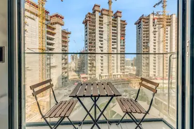 a table and chairs on a balcony with buildings at Stylish Apartments in a Vibrant Community in Dubai