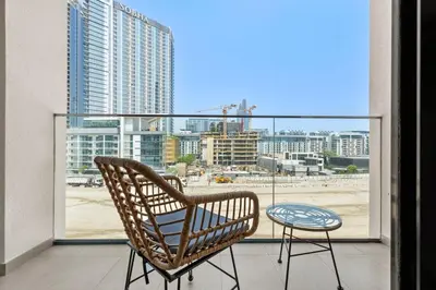 a chair and a table on a balcony with a view at Cozy Downtown Studio Dubai Retreat in Dubai