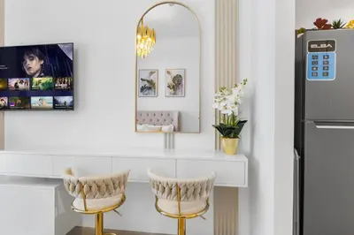 a kitchen with a white counter with two chairs and a mirror at Cozy Downtown Studio Dubai Retreat in Dubai