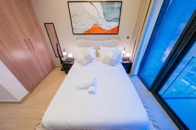 a bedroom with a bed with white sheets and a window at Stunning Studio with Swimming Pool View in Dubai