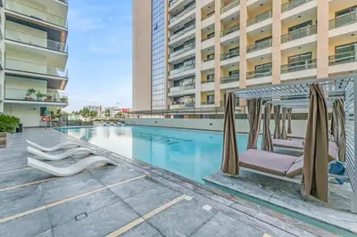 a swimming pool with chaise lounge chairs next to a building at 1 Bedroom Dream Stay- Binghatti in Dubai