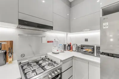 a kitchen with white cabinets and a stove top oven at 1 Bedroom Dream Stay- Binghatti in Dubai