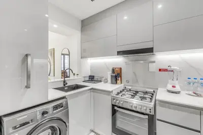 a white kitchen with a washing machine and a washer at 1 Bedroom Dream Stay- Binghatti in Dubai
