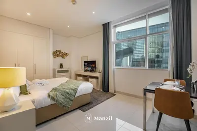 a bedroom with a bed and a desk and a window at Luxury Studio close to Dubai Mall and Burj Khalifa in Dubai