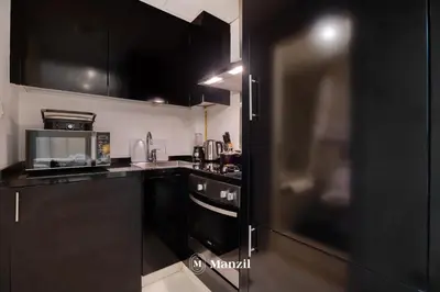 a kitchen with black cabinets and a black refrigerator at Luxury Studio close to Dubai Mall and Burj Khalifa in Dubai