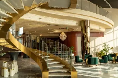a spiral staircase in a lobby with green chairs at Stylish 1BR in Damac by Paramount Business Bay in Dubai