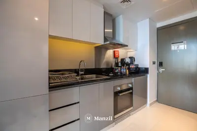 a kitchen with white cabinets and a stainless steel refrigerator at Waterfront Studio in Business Bay near Burj Khalifa in Dubai
