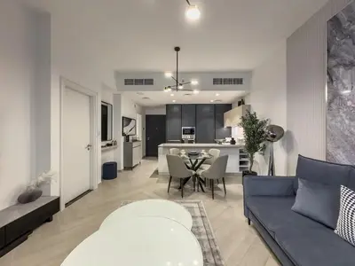 a living room with a blue couch and a kitchen at Amazing Brand New 1BR in Dubai
