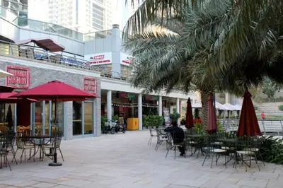 an outdoor patio with tables and chairs and umbrellas at GuestReady Holiday Homes - Industrial Chic in Dubai