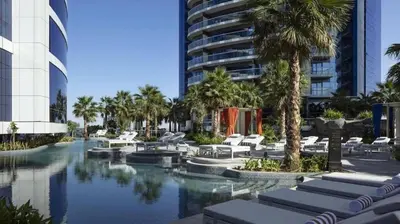 a resort pool with lounge chairs and palm trees at High Floor Burj Khalifa View Luxurious 1BR in Dubai