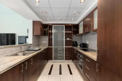 a large kitchen with wooden cabinets and a sink at Blakely Tower, Park Island, Dubai Marina - Mint Stay in Dubai