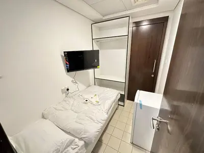 a small room with a bed and a refrigerator at Al Barsha Hostel for Girls in Dubai
