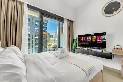 a white bedroom with a large window and a tv at Studio in Azizi with Free Pool and Gym Access in Dubai