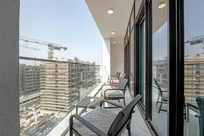 a balcony with chairs and a view of a building at 2BR Guest Favorite Elegant Apartment at Riviera 67 in Dubai