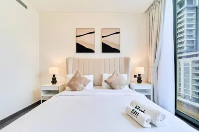a white bedroom with a large white bed with two lamps at FAM Living -Bright & Spacious Home in Sobha Hartland in Dubai